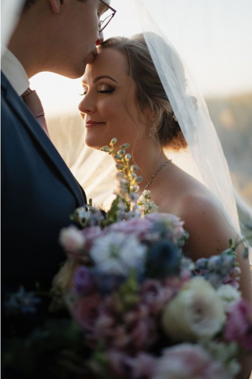Forehead kiss under the veil at golden hour